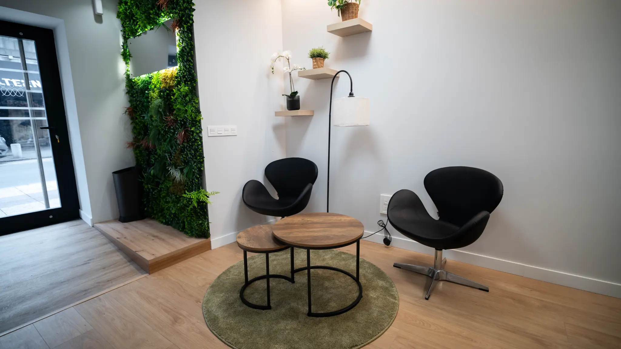 Zona de recepción con jardín vertical y butacas
